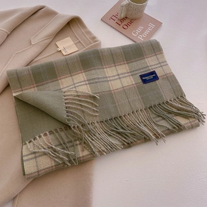 Detailed close-up of dark green plaid scarf with soft fringe and elegant classic texture