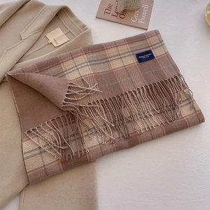 Detail of soft brown plaid scarf with fringe on wool coat for autumn styling