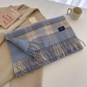Detail of blue-grey plaid cashmere-feel scarf with elegant woven label and tassels