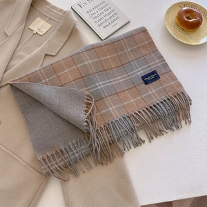 Detail of earthy plaid scarf with thick tassels and elegant classic woven label