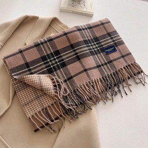 Macro detail of the woven texture and soft tassels on this plaid cashmere-feel scarf