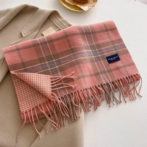 Detail of pink plaid scarf with fringe and elegant classic woven label texture