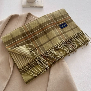 Detail of moss green plaid cashmere-like scarf with fringe on a beige coat