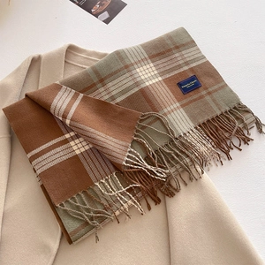 Detail of thick plaid scarf with tassels on beige wool coat background