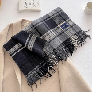 Detail of grey plaid scarf with Elegant & Classic tag resting on a beige coat