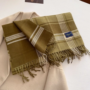 Macro detail of plaid scarf texture with olive green patterns and fringe on wool coat