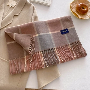 Detail of plaid scarf with fringe and 'Elegant & Classic' tag on beige wool coat