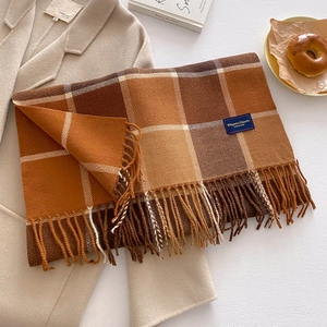 Detailed view of thick plaid scarf with tassels, warm orange and brown tones for winter
