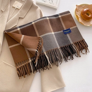 Close-up of thick knitted plaid scarf with long tassels and elegant brand label detail