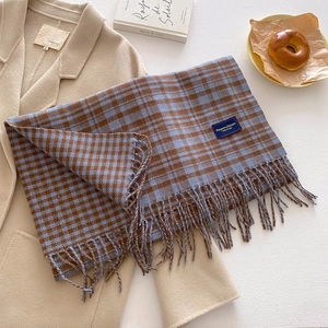 Detailed close-up of retro plaid scarf with fringes and elegant label on wool coat