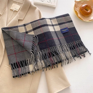 Classic plaid scarf with fringes styled on a beige coat for a cozy winter look