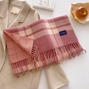 Close-up of pink and beige plaid scarf texture with thick fringe and brand tag