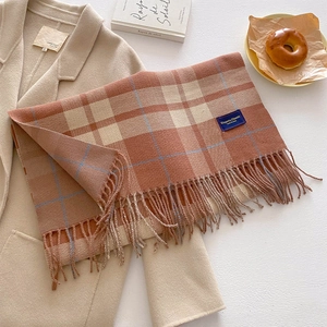 Detail of checkered cashmere scarf with fringe on a beige coat for a cozy winter look
