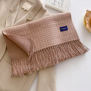 Detail of pink and brown houndstooth scarf with fringe tassels on a beige wool coat