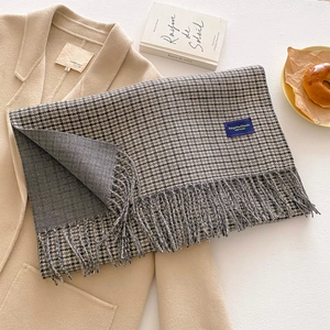 Vintage houndstooth scarf with tassels laid on a beige coat for a cozy winter aesthetic