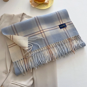 Detail of blue and beige checkered scarf with long fringe and elegant brand label