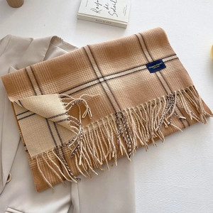 Close-up of earth tone plaid scarf with tassels and Elegant & Classic woven label