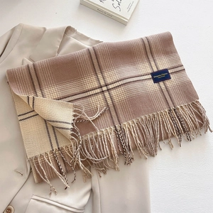 Detailed view of checkered scarf with elegant tassels on a beige blazer background