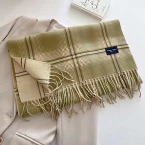 Detail of green and beige plaid scarf with tassels and elegant fabric label on a blazer