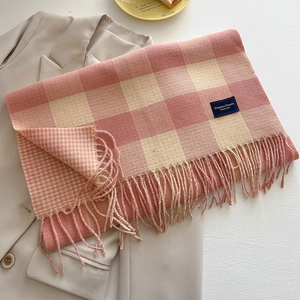 Detail eines rosa-beigen Karoschals aus Kaschmir mit Fransen und blauem Markenetikett