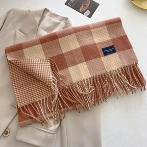 Nahaufnahme eines dicken karierten Strickschals mit Fransen und elegantem Textiletikett