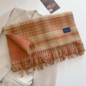 Classic plaid tassel scarf in orange and brown tones over a beige blazer