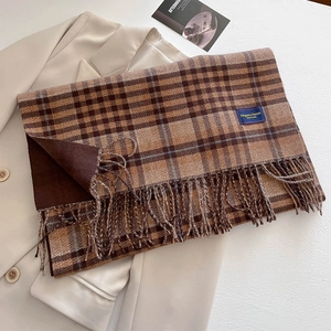 Close-up of brown plaid scarf with tassels and an Elegant & Classic label detail