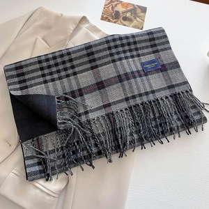 Detailed view of grey and red plaid cashmere-like scarf with long fringe and chic woven label