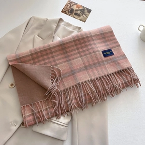 Detailed view of the soft plaid scarf with fringe tassels on a cream blazer