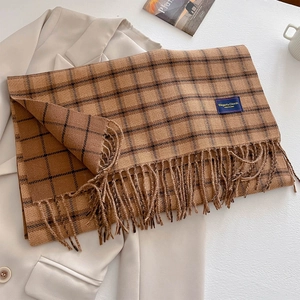 Detail showing vintage plaid scarf texture with elegant tassels and brand label