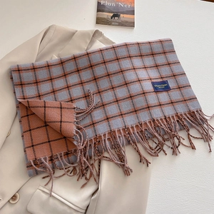 Detail of plaid scarf with fringe on a beige blazer and magazine, elegant texture