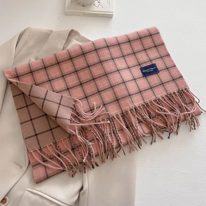 Pink and brown checkered scarf with fringe laid on a blazer with elegant classic label
