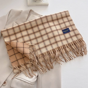Detail of plaid scarf featuring elegant fringe and woven label on wool blend fabric