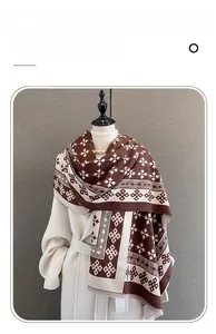 Dettaglio dei motivi geometrici jacquard e delle sottili frange della sciarpa effetto cashmere