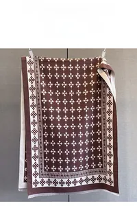 Dettaglio di sciarpa jacquard con motivi floreali geometrici e bordi a frange
