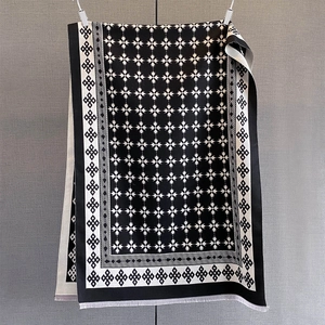 Dettaglio di sciarpa a motivi stellati bianchi e neri con delicate nappe di frange