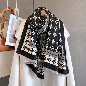 Dettaglio macro della sciarpa jacquard geometrica in bianco e nero con frange decorative