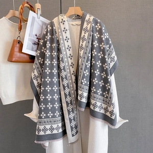 Dettaglio dello scialle in maglia grigio e bianco con motivi a stella e bordi a frange