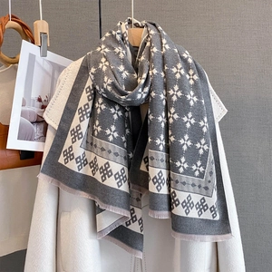Sciarpa jacquard retrò grigia e bianca con motivi geometrici e nappe su un cappotto