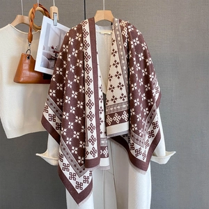 Sciarpa jacquard geometrica retrò marrone e crema con frange su un cappotto bianco