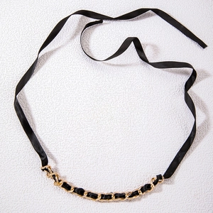 Detail of black satin ribbon necklace with intertwined gold chain and fabric texture