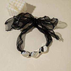Close-up of black organza bow necklace featuring three polished silver irregular beads