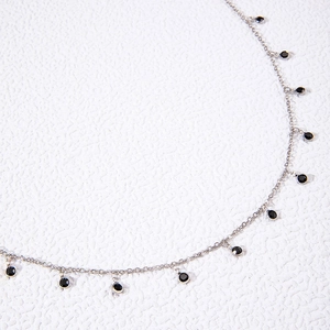 Close-up of a silver chain necklace featuring bezel-set round black zircon pendants