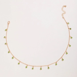 Detail of gold necklace featuring vibrant green round zircon beads with adjustable lobster clasp