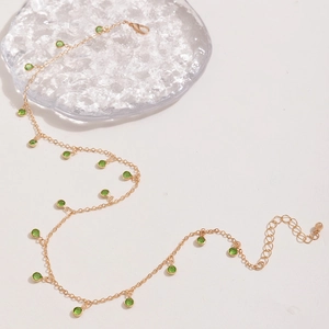 Detail of gold chain necklace with green faceted crystal beads and a lobster clasp