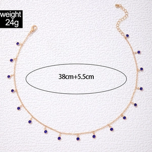 Detail of gold fringe necklace featuring blue round gems and lobster clasp closure