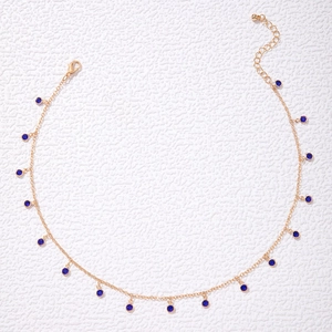 Detail of gold chain necklace featuring dark blue zircon pendants and lobster clasp