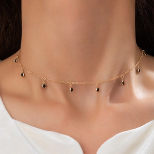 Elegant gold choker necklace with black bead and teardrop pendants on model collarbone