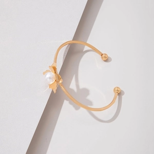 Détail d'un bracelet jonc fleur dorée avec perle centrale et incrustation turquoise