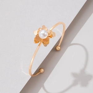 Détail d'un bracelet ouvert doré avec une fleur en perles et une finition métallique